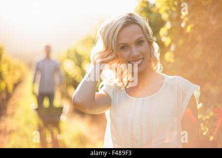 Portrait of smiling woman standing in front ou son homme poussant une brouette Banque D'Images