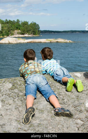Deux garçons couchés sur un rocher, la Suède. Banque D'Images