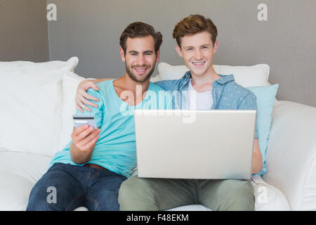 Cute couple shopping online with laptop on couch Banque D'Images