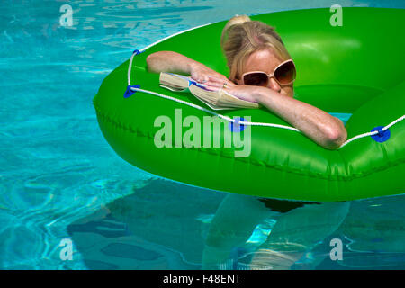 Femme en vacances de détente sur un anneau de caoutchouc dans une piscine Banque D'Images