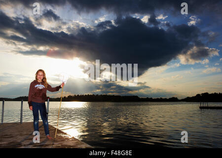 Fille avec un filet à poche sur une jetée, la Suède. Banque D'Images