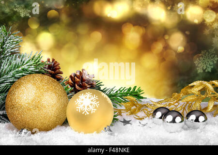 Scène de Noël glamour avec des ornements d'or, les branches de sapin et des pommes de pin sur la neige et brillant or defocused lights dans le dos Banque D'Images
