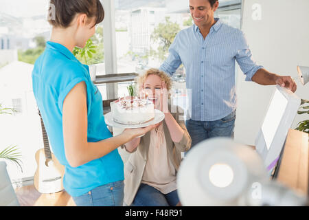 Woman blowing out candles on cake Banque D'Images