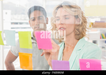 Young businesspeople pointing at sticky notes Banque D'Images