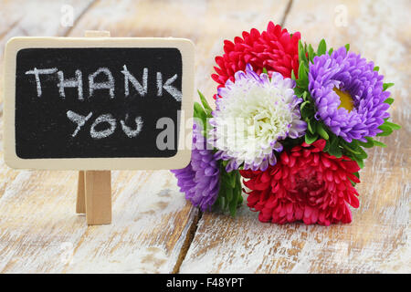 Merci écrit sur petite ardoise avec bouquet de fleurs aster colorés Banque D'Images