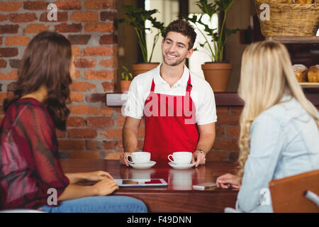 Smiling waiter sert du café aux clients Banque D'Images