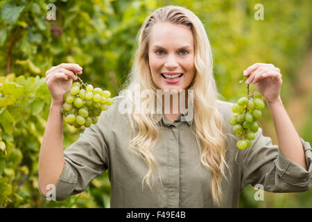 Vigneron Smiling blonde holding grapes Banque D'Images