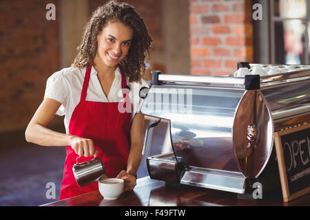 Smiling barista de verser le lait dans une tasse Banque D'Images