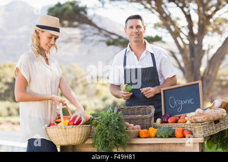 Smiling farmer vente de poivrons rouges et verts Banque D'Images