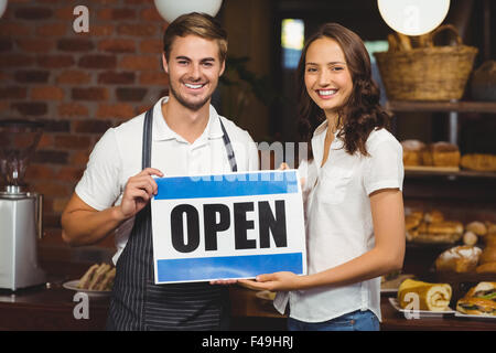 L'équipe souriante posant avec open sign Banque D'Images