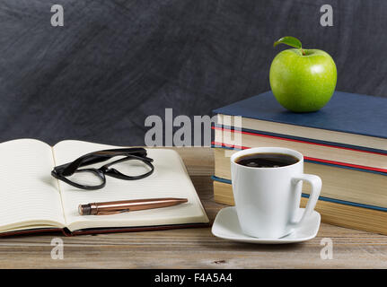 Close up d'un bureau rustique d'enseignant avec livres, papier, stylo, café, lunettes de lecture d'une longue avec une pomme verte en face de ch Banque D'Images