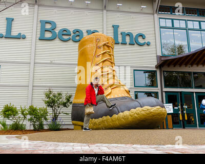 Woman leaning on l'énorme démarrage emblématique L.L. Bean à l'extérieur de leur magasin à Freeport, Maine Banque D'Images