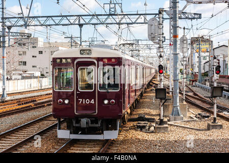 Le Japon, Hankyu railway privé. Maroon Express train arrivant en gare de Nishinomiya, jour, soleil, ciel bleu. Banque D'Images