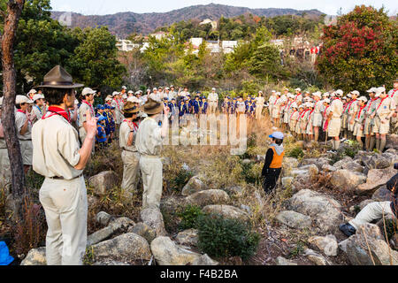 Le Japon. Scouts de garçon debout sur la montagne, saluant et en faisant des contributions lors de l'aube pendant le lever du soleil afin d'accueillir le soleil pour le jour de l'an. Banque D'Images