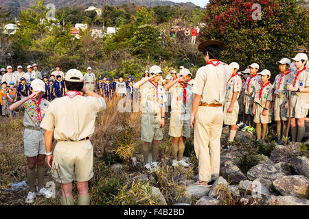 Le Japon. Scouts de garçon debout sur la montagne, saluant et en faisant des contributions lors de l'aube pendant le lever du soleil afin d'accueillir le soleil pour le jour de l'an. Banque D'Images