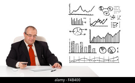 Businessman sitting at desk avec schémas et tenant une mobilephone Banque D'Images