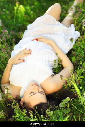 Beautiful pregnant woman relaxing on grass Banque D'Images
