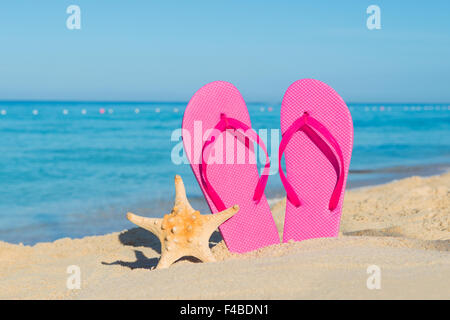 Le voyage par bateau. Vacances à la plage. Les tongs roses et de sable de mer sur la mer. Banque D'Images