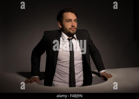 Businessman climbing out d'un trou circulaire Banque D'Images