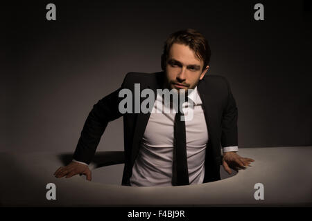 Businessman climbing out d'un trou circulaire Banque D'Images