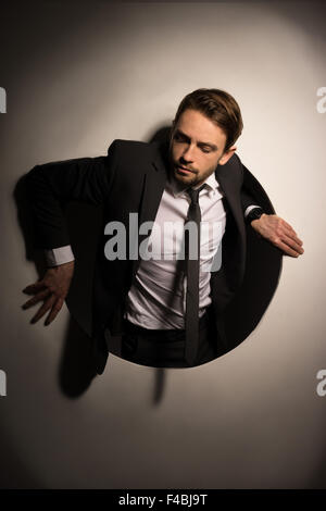 Businessman climbing out d'un trou circulaire Banque D'Images