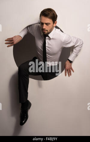 Businessman climbing out d'un trou circulaire Banque D'Images