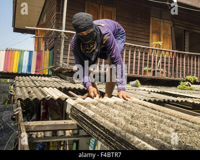 Bangkok, Thaïlande. 16 Oct, 2015. Un travailleur de démolition commence le démontage du toit d'une maison dans le Wat Kalayanamit quartier. Le propriétaire a été expulsé de la Chambre quelques minutes plus tôt. Cinquante-quatre maisons autour de Wat Kalayanamit, un temple bouddhiste historique sur le Chao Phraya, dans la section de Thonburi, Bangkok sont rasées et les résidents expulsés pour faire place à de nouveaux aménagements au temple. L'abbé du temple a dit qu'il a été l'éviction des résidents, qui ont vécu sur les jardins du temple depuis des générations, parce que leurs maisons sont dangereux et parce qu'il veut améliorer le temple Banque D'Images