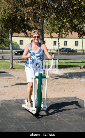 Femme adulte avec sunglaeese sur la formation à l'extérieur dans le parc de vélo elliptique à Lisbonne Portugal Banque D'Images