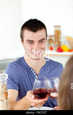 Beau jeune homme après avoir manger avec sa petite amie boire du vin à la maison dans la cuisine Banque D'Images