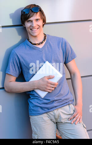 Smiling student boy leaning against wall moderne Banque D'Images