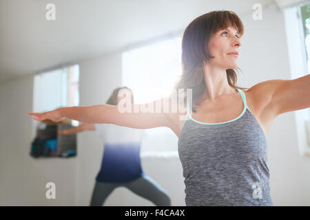 Remise en forme de couple. Les femmes exerçant au cours de yoga. Virabhadrasana poser. Banque D'Images