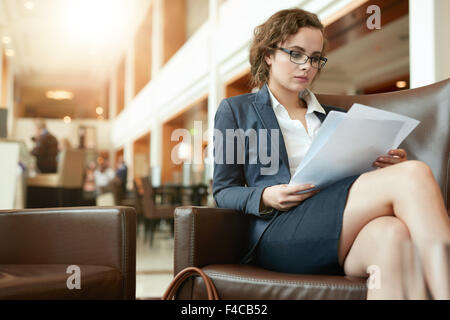 Portrait de jeune femme occupée à lire des documents contractuels. Businesswoman sitting at cafe aller au moyen de rapports d'activités. Banque D'Images