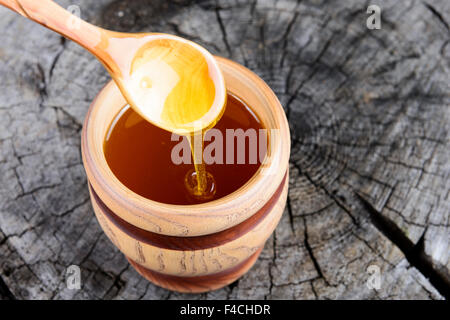 Pot de miel et une cuillère de miel sur un fond de bois Banque D'Images