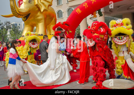 Yantai, Shandong, Chine. Un couple nouvellement marié passez par les mouvements de leur célébration de mariage coloré. Banque D'Images