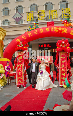 Yantai, Shandong, Chine. Un couple nouvellement marié passez par les mouvements de leur célébration de mariage coloré. Banque D'Images