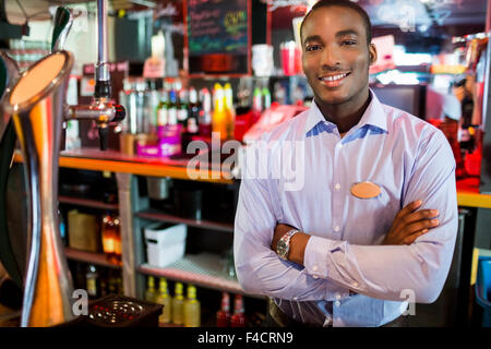 Barman souriant posant près de tap Banque D'Images