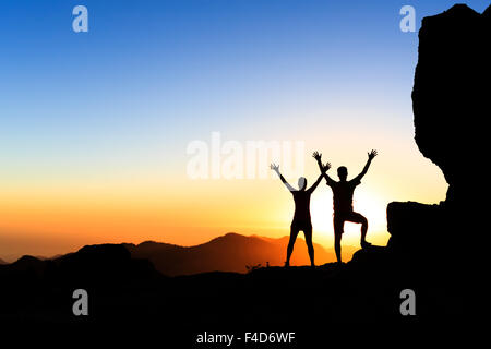 Les randonneurs en couple succès coucher de montagnes, accomplir avec les bras tendus. Jeune homme et femme sur la chaîne de montagnes rocheuses loo Banque D'Images