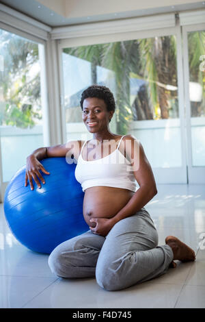 Portrait of smiling pregnant woman leaning on exercise ball Banque D'Images