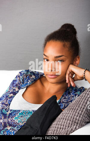 Teenage girl sitting in a la table en appareil photo avec un sourire amical Banque D'Images