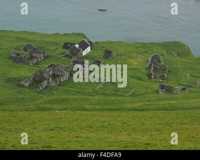 Vue de haut de la maison blanche et les ruines des habitations en pierre abandonnée sur une grande île Blasket, Irlande avec fond de l'océan Atlantique Banque D'Images