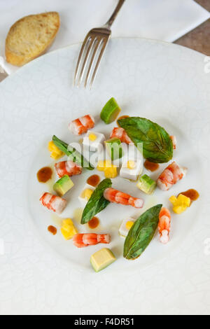 Gambas, avocat et noix de coco dans une assiette, basilic séché Banque D'Images