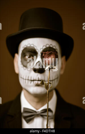 Portrait d'un jeune homme avec le maquillage, le port de calaveras noeud papillon et haut de forme, avec une rose à l'avant de l'œil, avec un vintage Banque D'Images