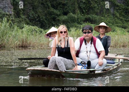 L'homme et de la femme vietnamienne bateau à rames avec deux touristes de l'ouest le long de la rivière ngo dong,Tam Coc,Ninh Binh, Vietnam Banque D'Images