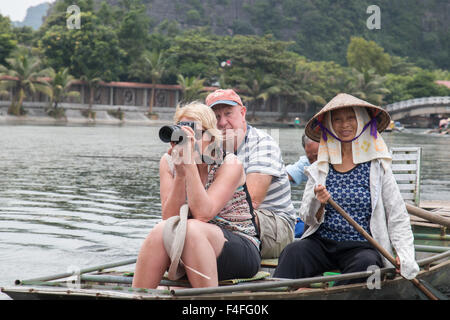 L'homme et de la femme vietnamienne bateau à rames avec deux touristes de l'ouest le long de la rivière ngo dong,Tam Coc,Ninh Binh, Vietnam Banque D'Images