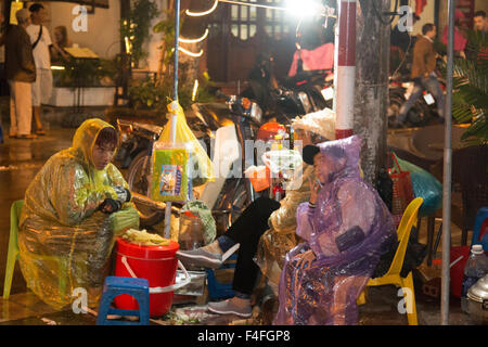 Les Vietnamiens préparant de la nourriture de rue sous la pluie dans le vieux quartier de Hanoi, la capitale, le Vietnam, l'Asie portant des manteaux en plastique de pluie Banque D'Images