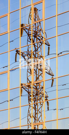 Tour électrique haute tension se reflète dans les fenêtres de l'immeuble en miroir Banque D'Images