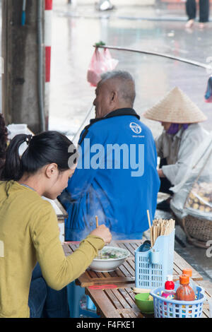 Dame vietnamienne de manger la soupe de nouilles Pho,plat traditionnel,pour le petit-déjeuner dans la rue Ta Hien, vieux quartier de Hanoi, Vietnam Banque D'Images