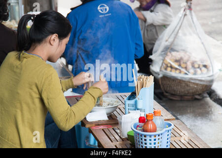 Dame vietnamienne de manger la soupe de nouilles Pho,plat traditionnel,pour le petit-déjeuner dans la rue Ta Hien, vieux quartier de Hanoi, Vietnam Banque D'Images