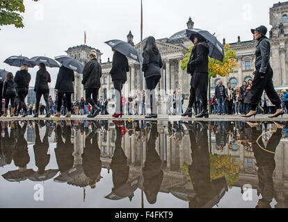 Berlin, Allemagne. 17 Oct, 2015. Les participants ont mis en miroir par une flaque comme ils marchent devant le Reichstag bâtiment parlementaire au cours de la marche "pour la liberté" organisé à Berlin, Allemagne, 17 octobre 2015. L'événement était organisé par la campagne "A21" pour attirer l'attention sur les 27 millions d'hommes, femmes et enfants en esclavage, un jour avant la Journée européenne contre la traite des êtres humains. Photo : PAUL ZINKEN/dpa/Alamy Live News Banque D'Images