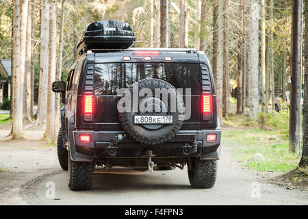 Saint-pétersbourg, Russie - 11 octobre 2015 : Noir Hummer H2 véhicule passe sur les route de campagne et forêt russe, vue arrière Banque D'Images